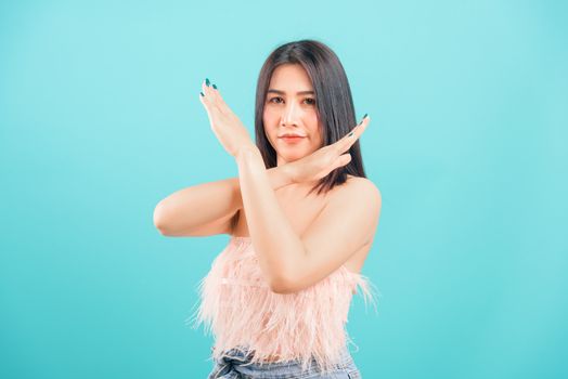 Asian beautiful woman her showing say no hand sign looking to camera on blue background, with copy space for text