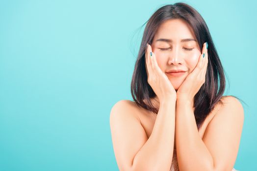 Smiling face Asian beautiful woman her touching face skin care on blue background, with copy space for text