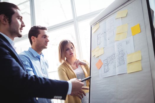 Business people looking at blueprints on board in creative office