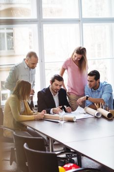 Business people with blueprint in meeting room at creative office