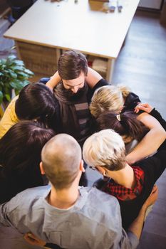 High angle view of creative business people forming huddle in office