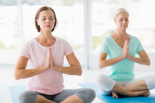 Women with eyes closed performing yoga at fitness studio