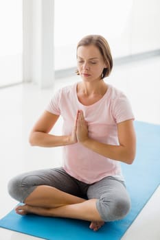 Young woman peforming yoga at fitness studio