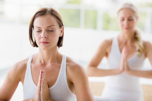 Women with eyes closed doing yoga at health club