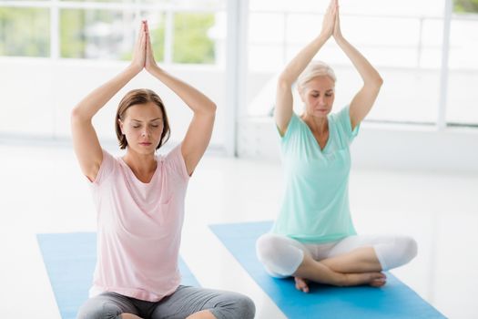 Women with hands clasped doing yoga at fitness studio