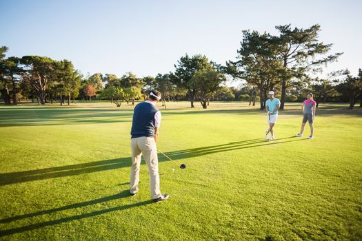 People playing golf while standing on field