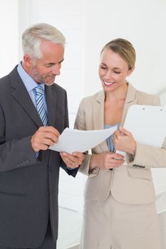 Smiling estate agent going over contract with customer in empty house