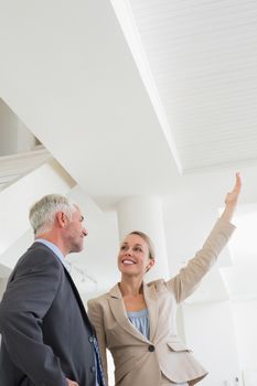 Smiling estate agent showing ceiling to potential buyer in empty house
