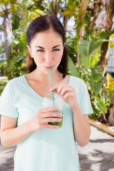 Portrait of woman having juice while standing outdoors