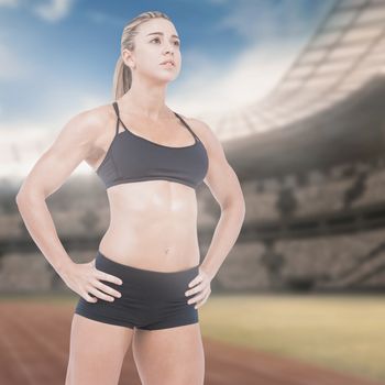 Female athlete posing with hands on hip against view of a stadium