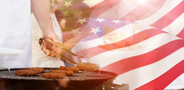 Barbecue grill with extended family having lunch in park against waving flag of america