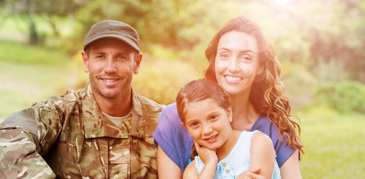 Portrait of smiling army man with family while sitting in park