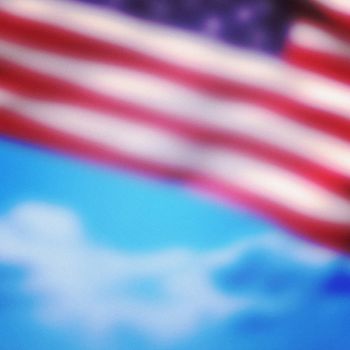 Close-up of American flag against cloudy sky background