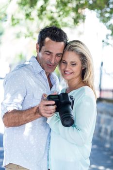 Cheerful couple looking in camera while standing outdoors