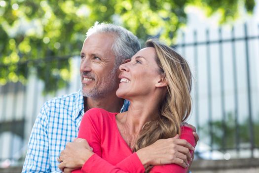 Romantic mature couple standing against fence in city