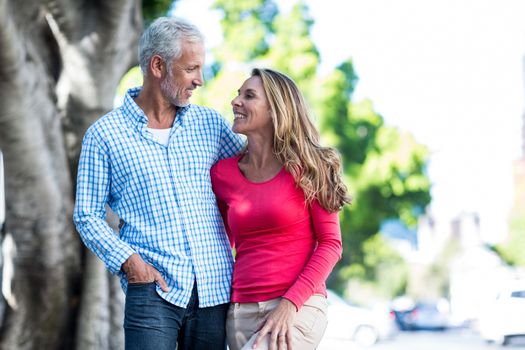 Front view of romantic mature couple standing against tree in city