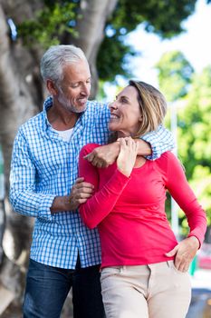 Front view of romantic mature couple standing against tree in city