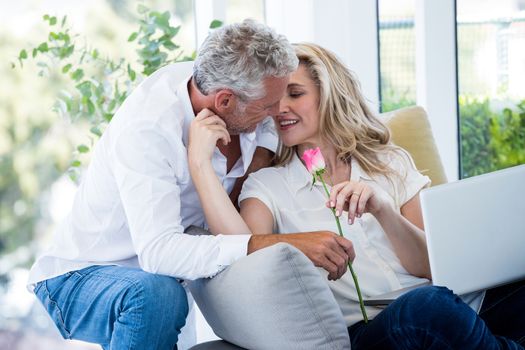 Romantic mature man giving rose to woman at home