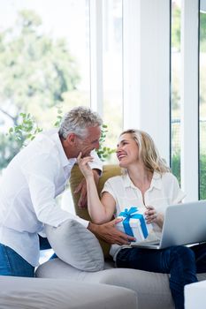 Romantic couple with gift and laptop at home