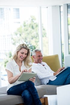 Happy mature couple using technology while sitting at home