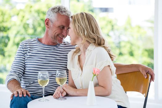 Romantic mature couple with white wine while sitting at restaurant