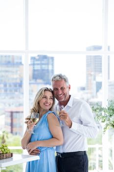 Romantic mature couple holding wine while standing at restaurant