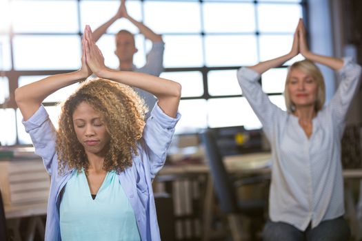 Creative business people practicing yoga in office