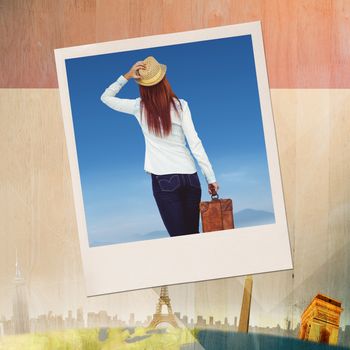 Rear view of hipster woman holding suitcase against colored background