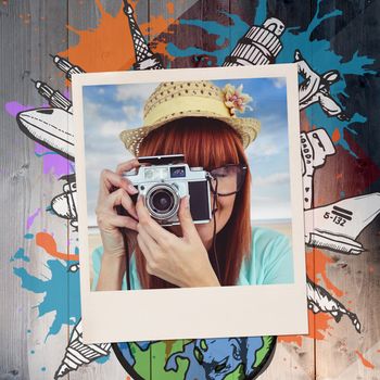Portrait of a smiling hipster woman holding retro camera against colored wood