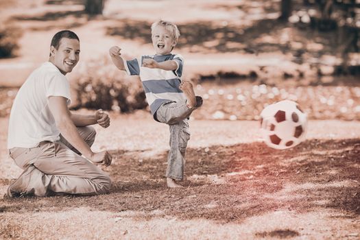 Father watching son kicking football