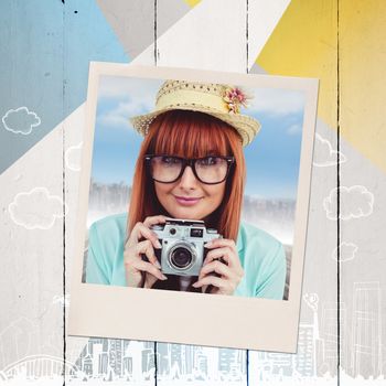 Portrait of a smiling hipster woman holding retro camera against colored wood