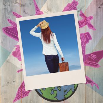 Rear view of hipster woman holding suitcase against colored wood