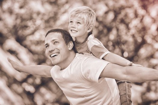 Father giving son a piggy back in park