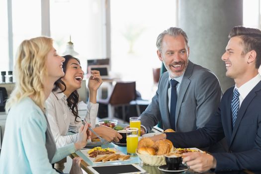 Business people interacting with each other while having meal in restaurant