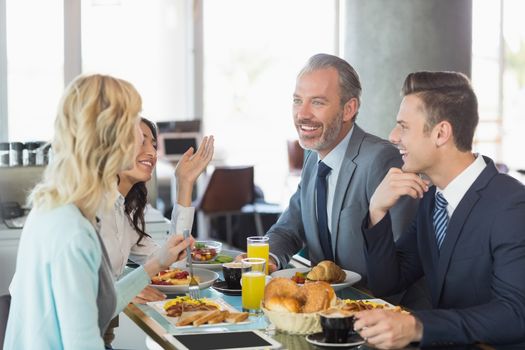 Business people interacting with each other while having meal in restaurant