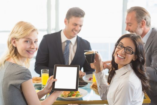 Portrait of business people using digital tablet while having meal in restaurant