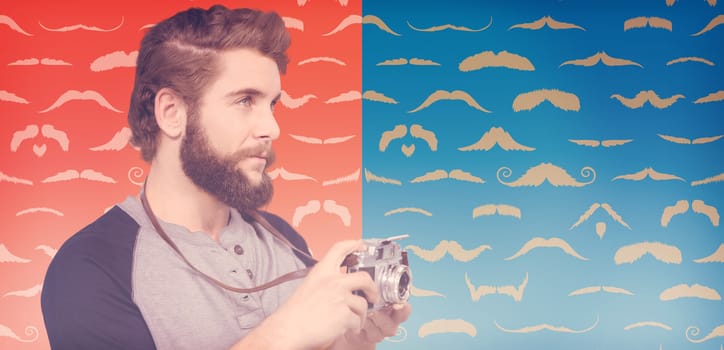 Hipster using digital camera  against composite image of mustaches