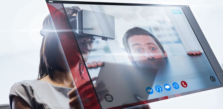 Nervous businessman peeking over desk against businesswoman looking her tablet while using a virtual glasses