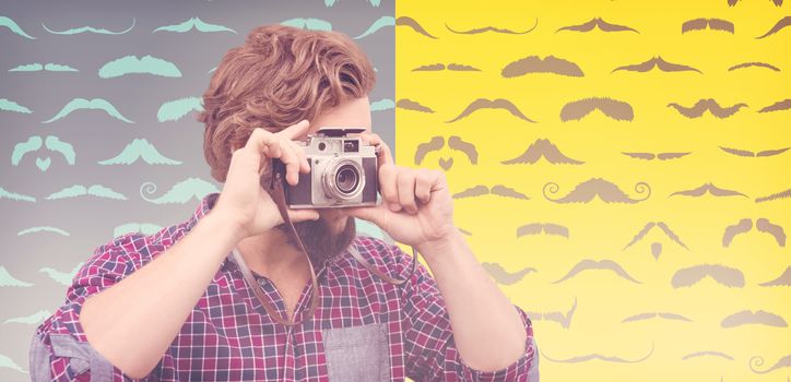 Hipster photographing with camera against composite image of mustaches