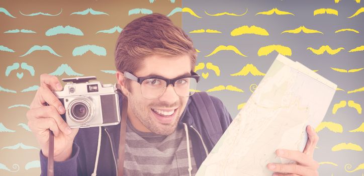 Portrait of happy man holding map and camera against composite image of mustaches