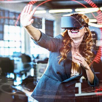 Cheerful woman gesturing while using virtual reality simulator in office