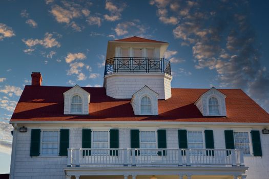 An old coastal house with a widows walk and red roof