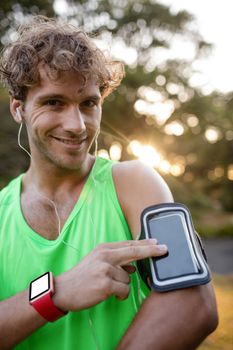 Portrait of smiling jogger listening to music from mobile phone in park
