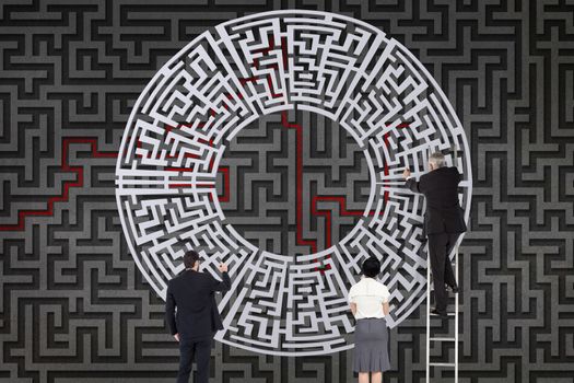 Businesspeople drawing a maze against grey background