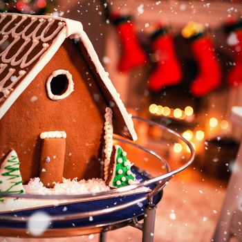 Snow falling against gingerbread house on table