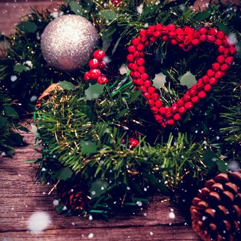 Snow falling against grapevine wreath with red ribbon and decoration