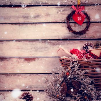 Snow falling against hanging wreath with basket full of decoration