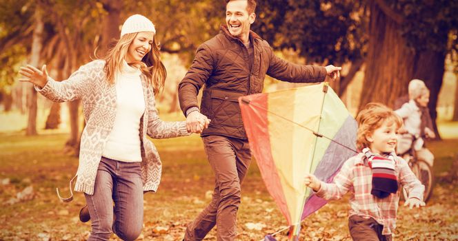 Young family playing with a kite on an autumns day