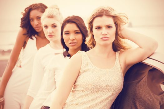 Portrait of female friends posing while leaning on limousine at outdoors