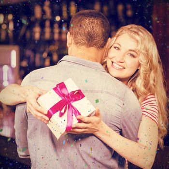 Woman holding present while hugging boyfriend against flying colours